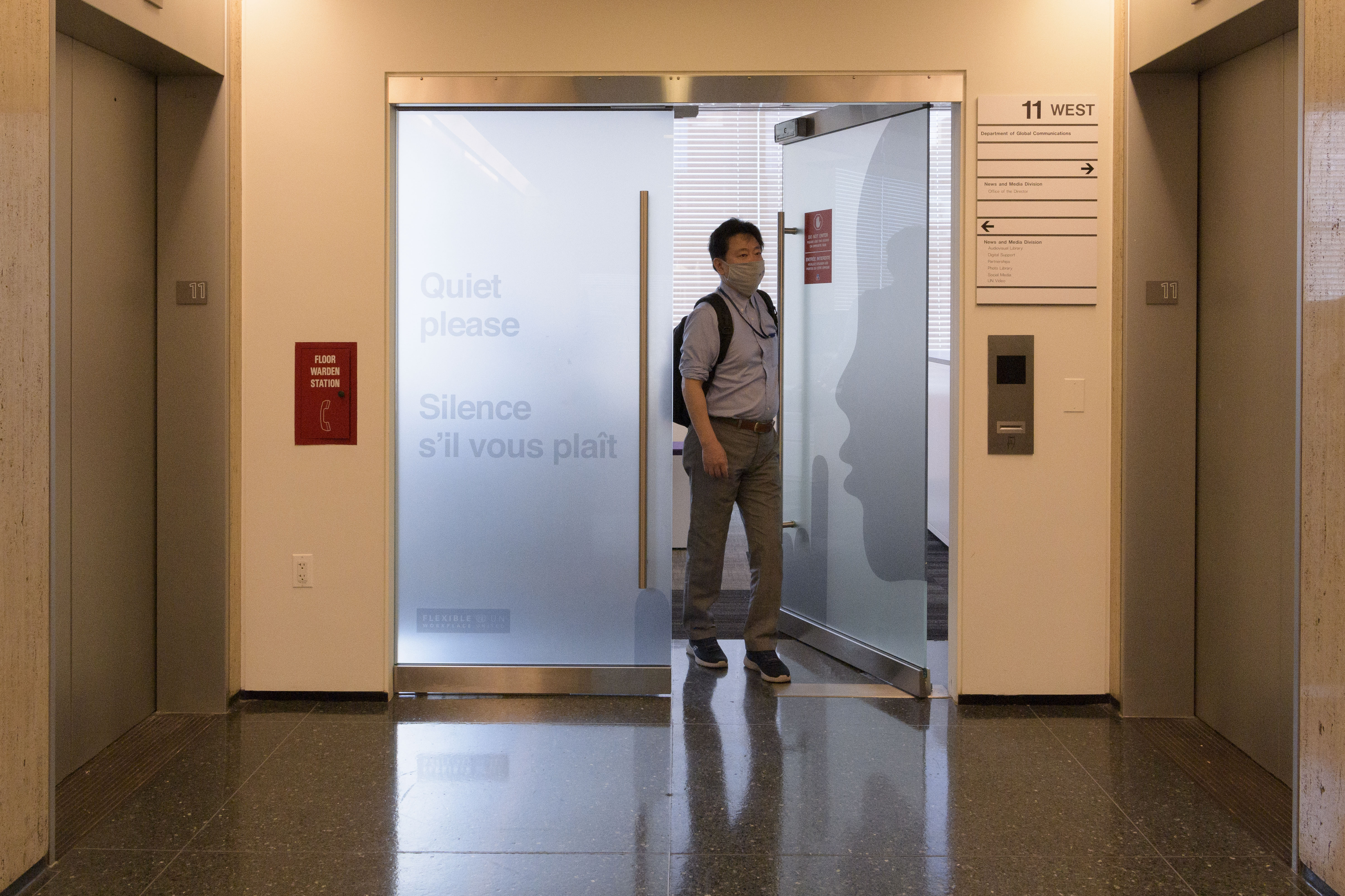 Man walks through glass doors into an elevator bank.
