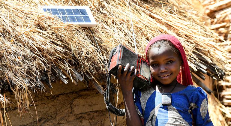 une petite fille avec un appareil audio branché à un petit panneau solaire