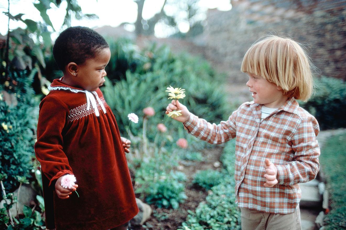 Un niño dándole una margarita a una niña
