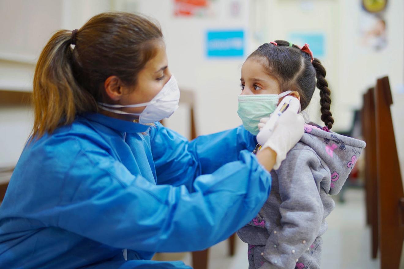International Universal Health Coverage Day A nurse takes a girl’s temperature