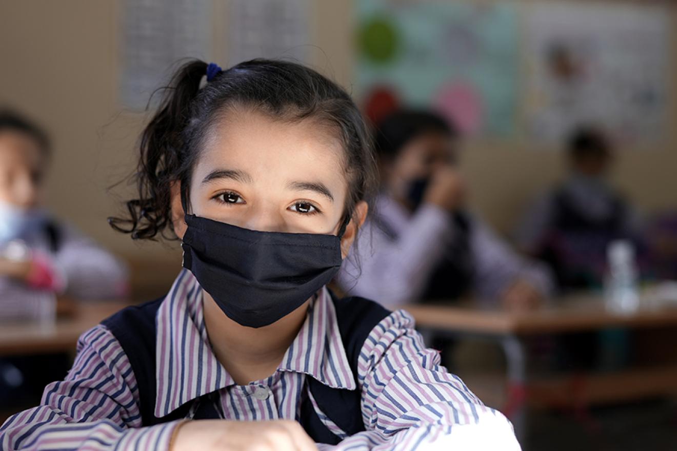 Une fillette portant un masque dans une salle de classe