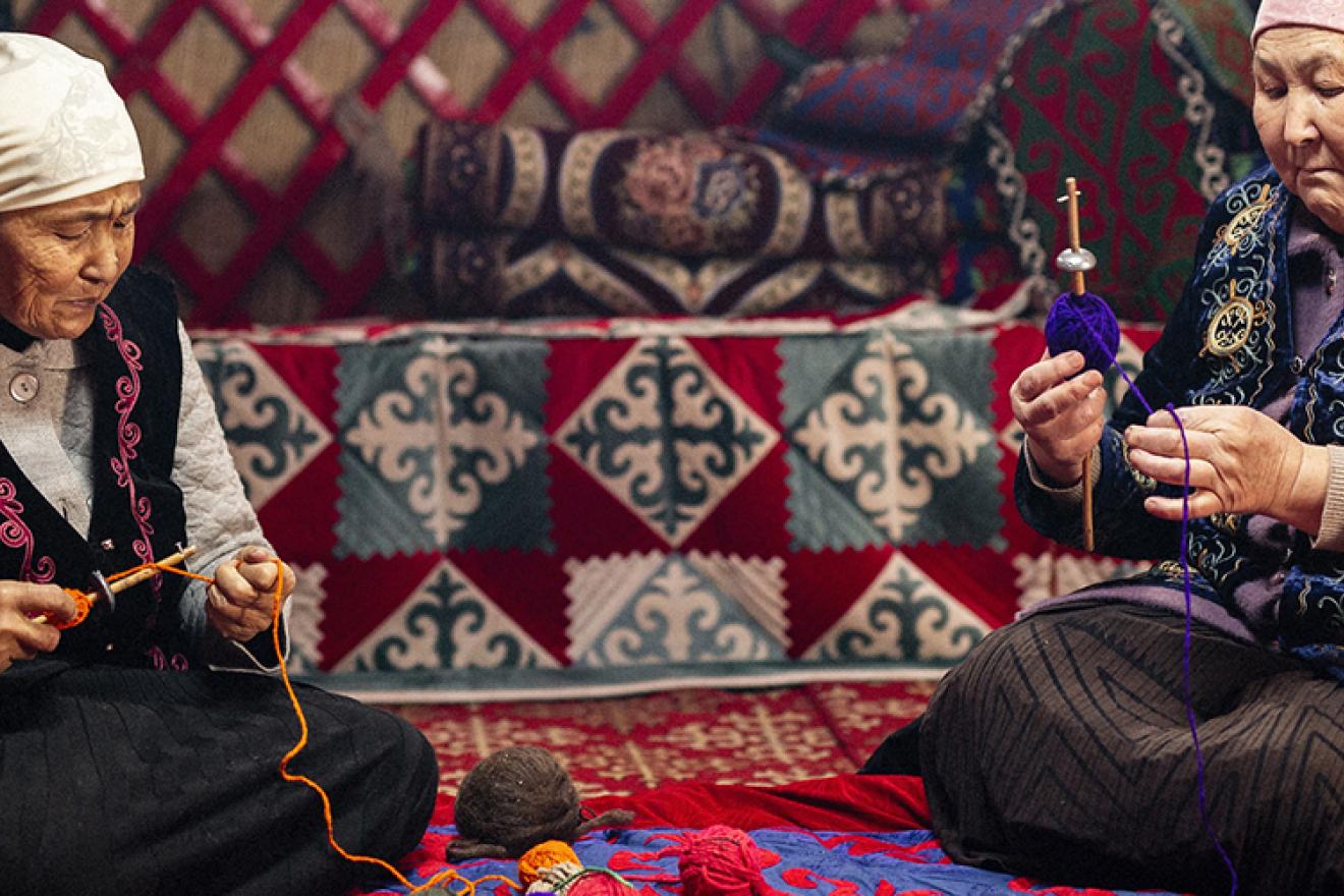 Two women are working on iyik - national technique for thread making.