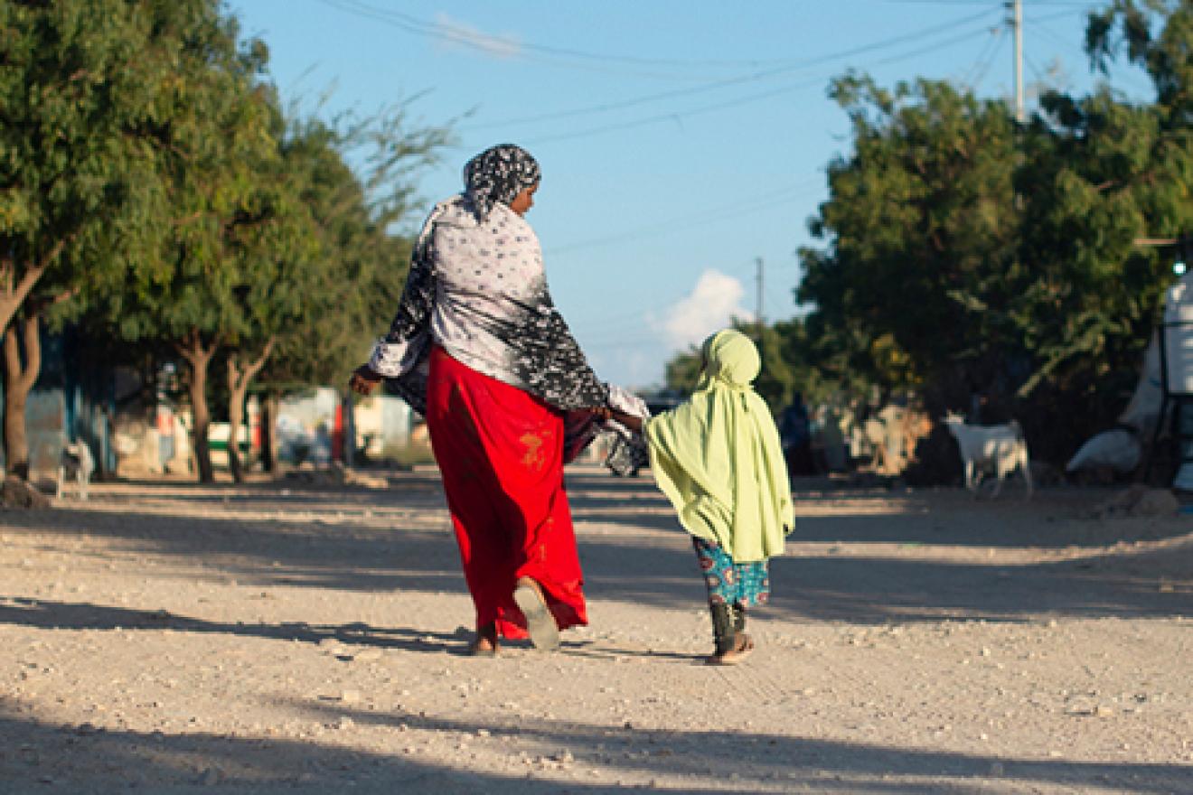 Une femme marche en tenant sa fille par la main