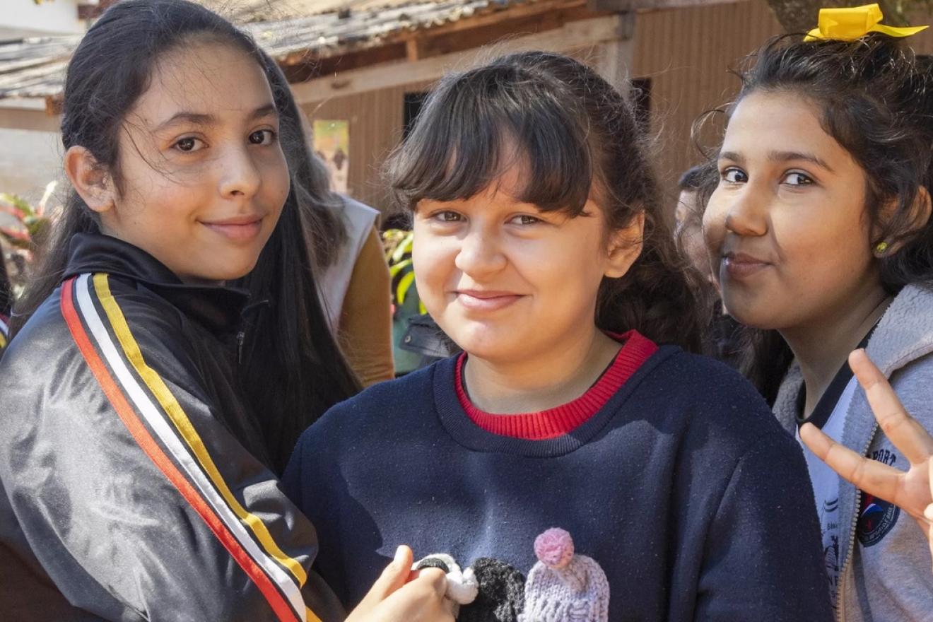Tres niñas paraguayas sonríen a la cámara. 