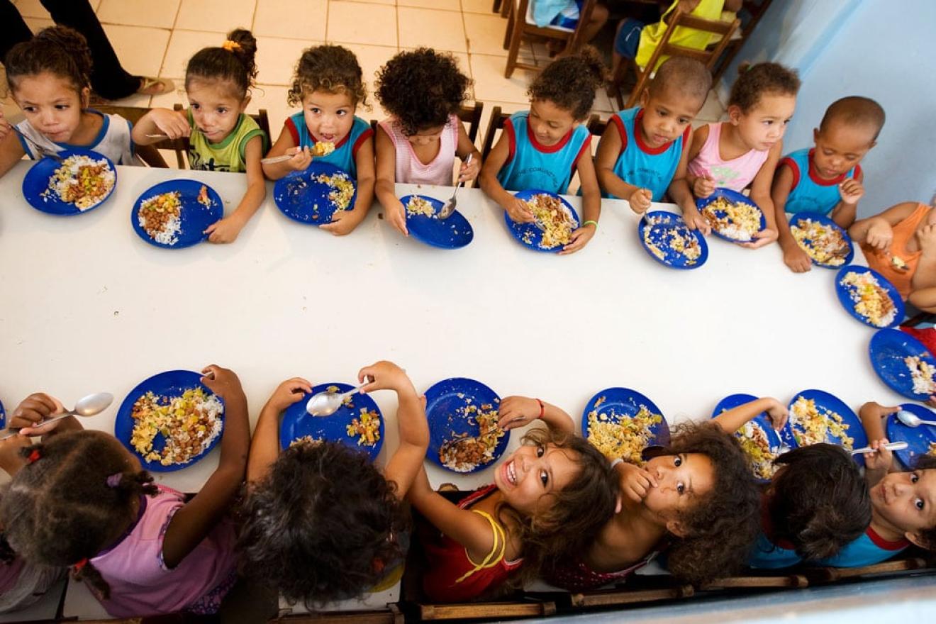 Varios niños comen en una mesa escolar. 