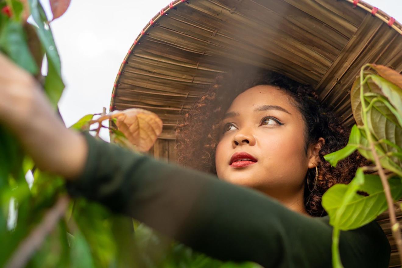 Una campesina joven trabaja en el campo protegida contra el sol por un sombrero en forma de cono.