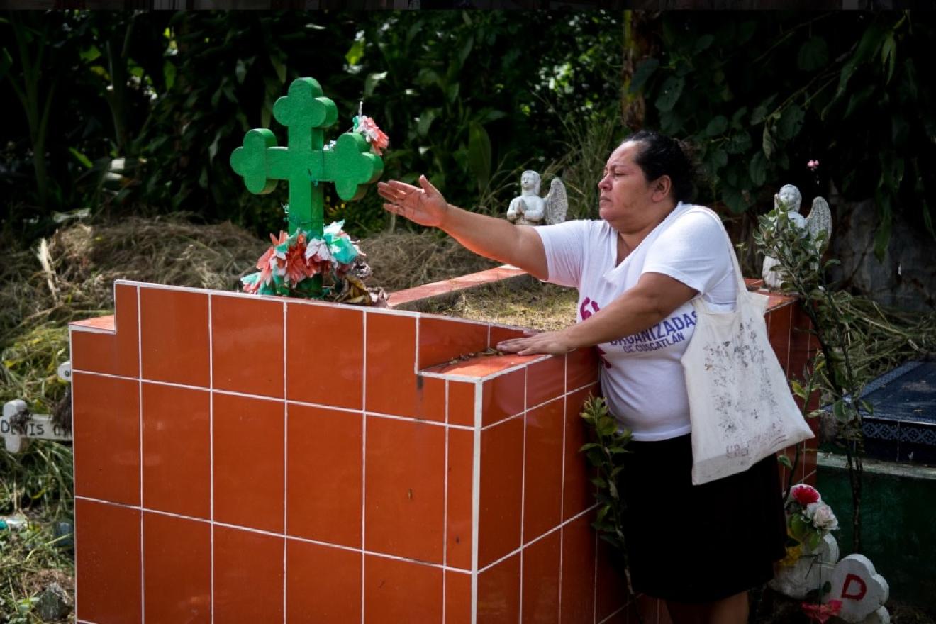 Una madre junto a la tumba de su hija, asesinada por su esposo en la ciudad salvadoreña de San Vicente.