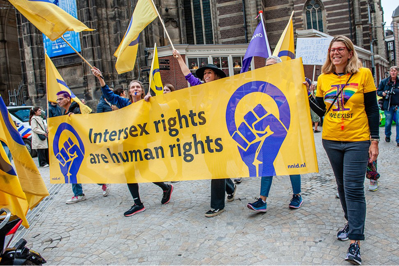 Des personnes manifestent en tenant una grande bannière pour les droits des personnes intersexes
