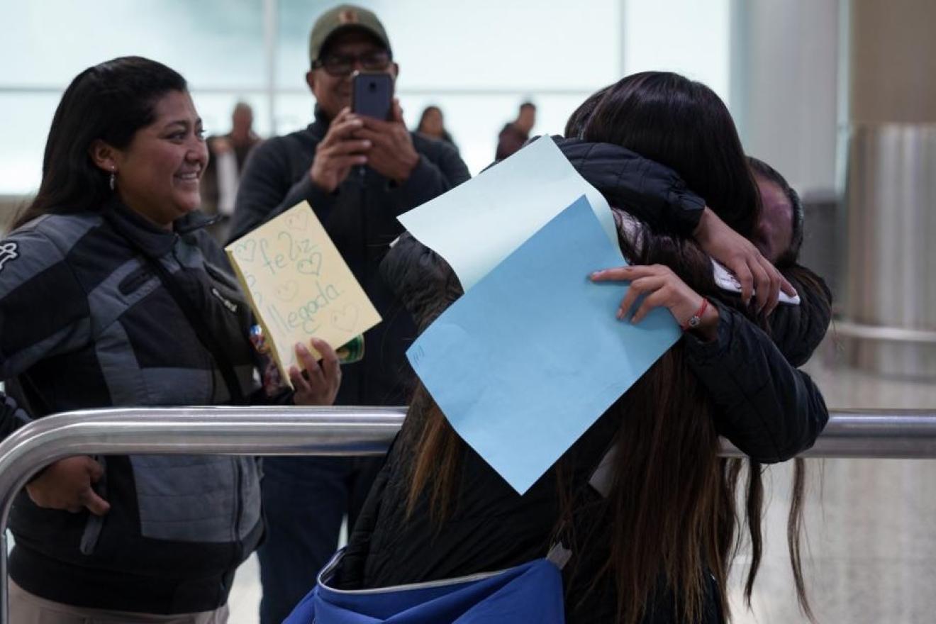 Unos familiares dan la bienvivida en un aeropuerto a una migrante recién regresada.