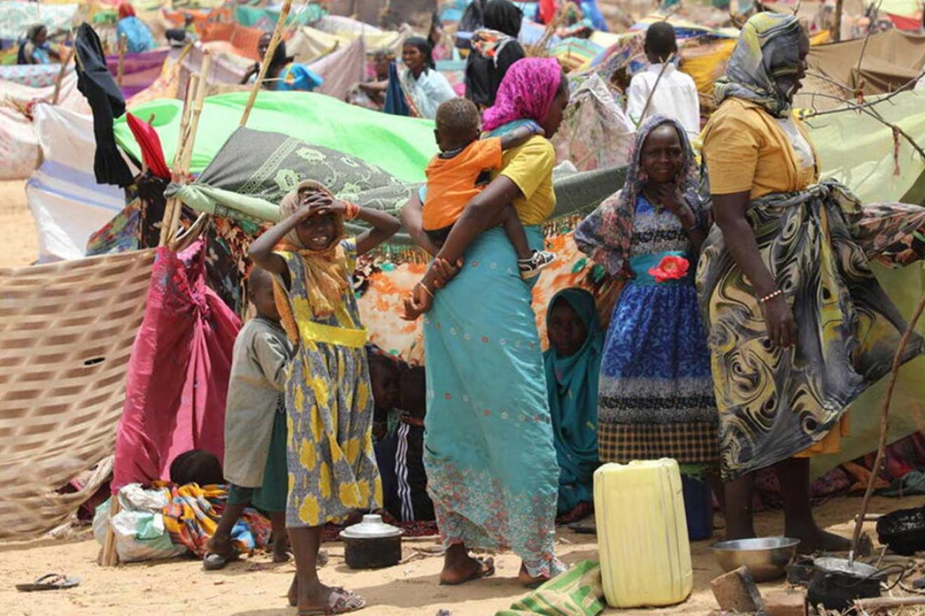 Un camp de réfugiés soudanais avec des femmes en premier plan portant des vêtements colorés