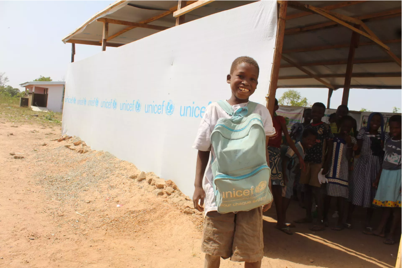 Un enfant africain avec un sac à dos UNICEF sourit à la caméra