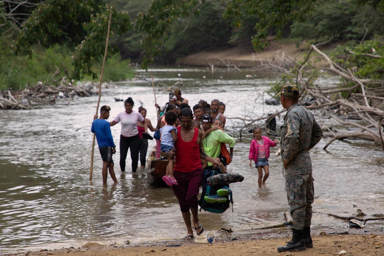 Varias familias cruzan un rio a pie en la selva de Darién.
