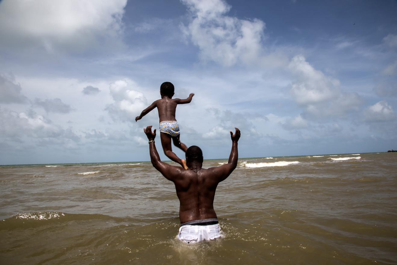 Un enfant joue avec son père sur une plage.