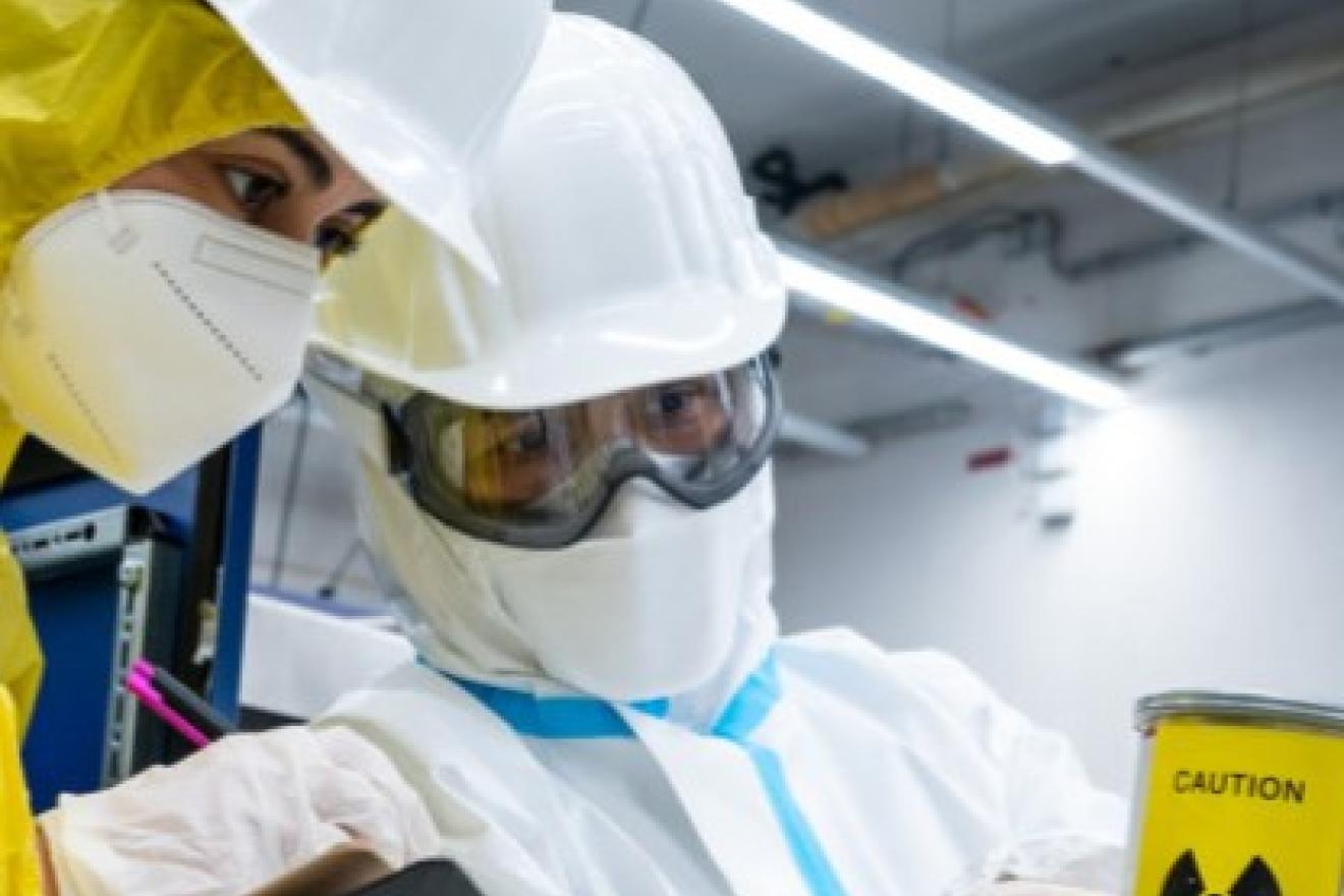 Deux inspecteurs nucléaires examinent un objet portant le symbole de danger radioactif