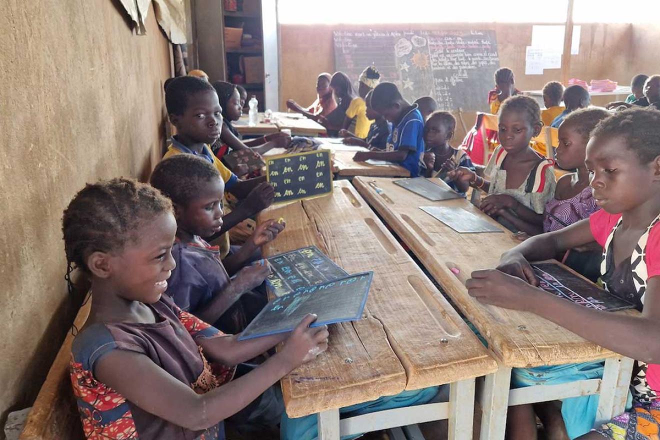 Des étudiants dans une salle de classe au Kenya sourient à la caméra