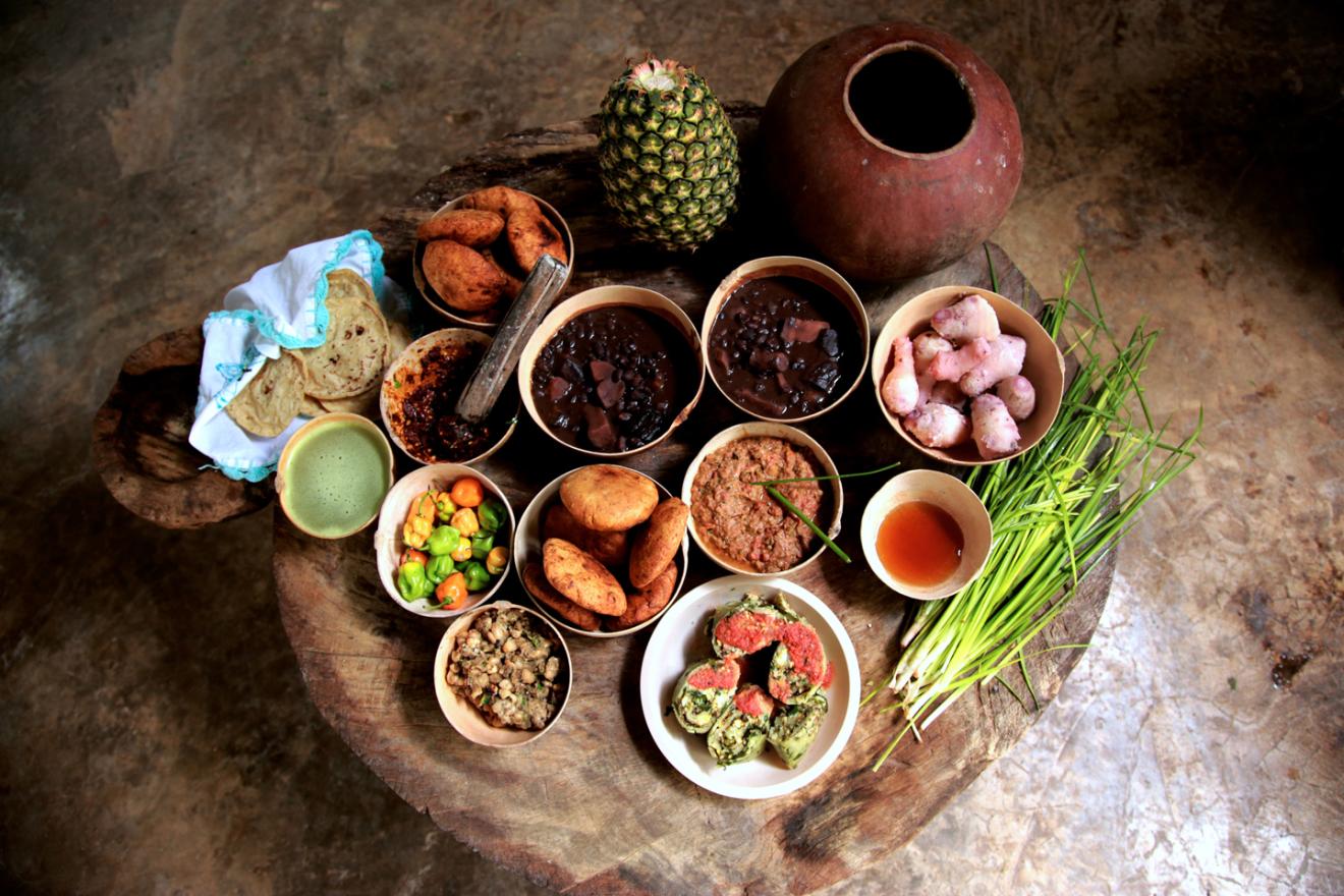 Pequeña mesa baja tradicional mexicana repleta de platillos con productos y platos de la cocina del país.  