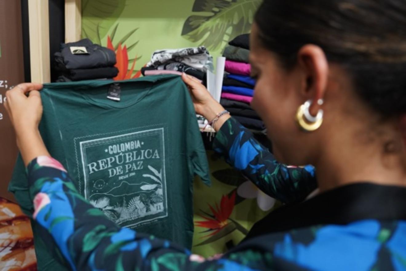 Una mujer sostiene y observa una camiseta con el mensaje: ‘Colombia, República de Paz’.