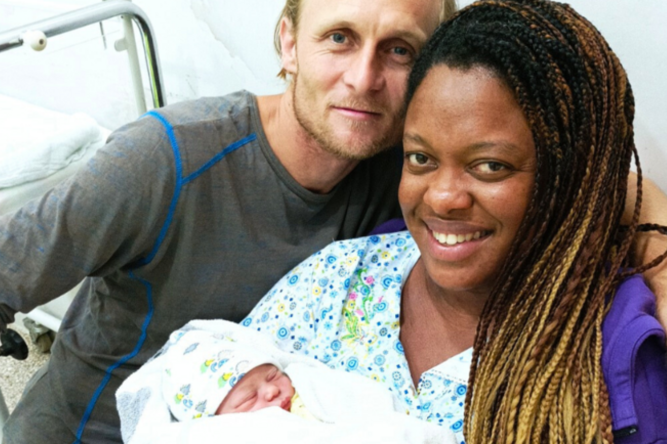 Geydis posa en el hospital junto a su bebe recién nacido y su marido.