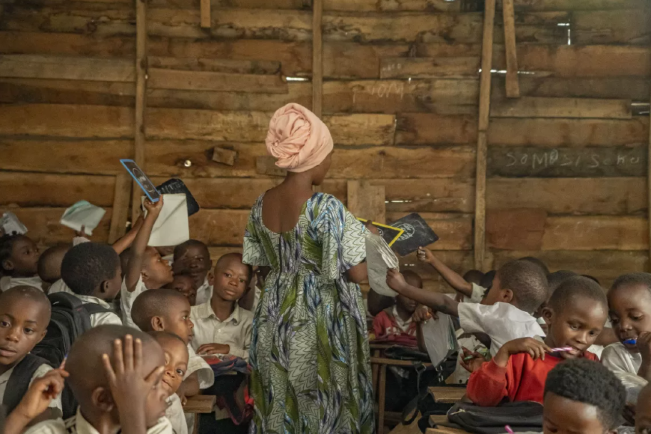 Une jeune femme de dos, devant une classe d'école en Afrique