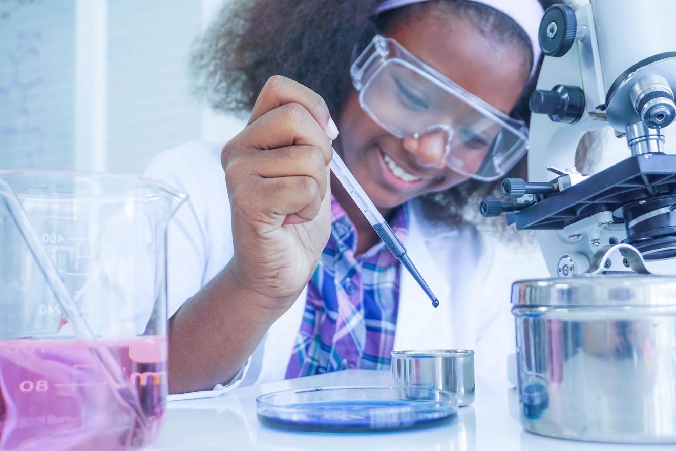 Young African scientist testing a liquid chemical in a laboratory.