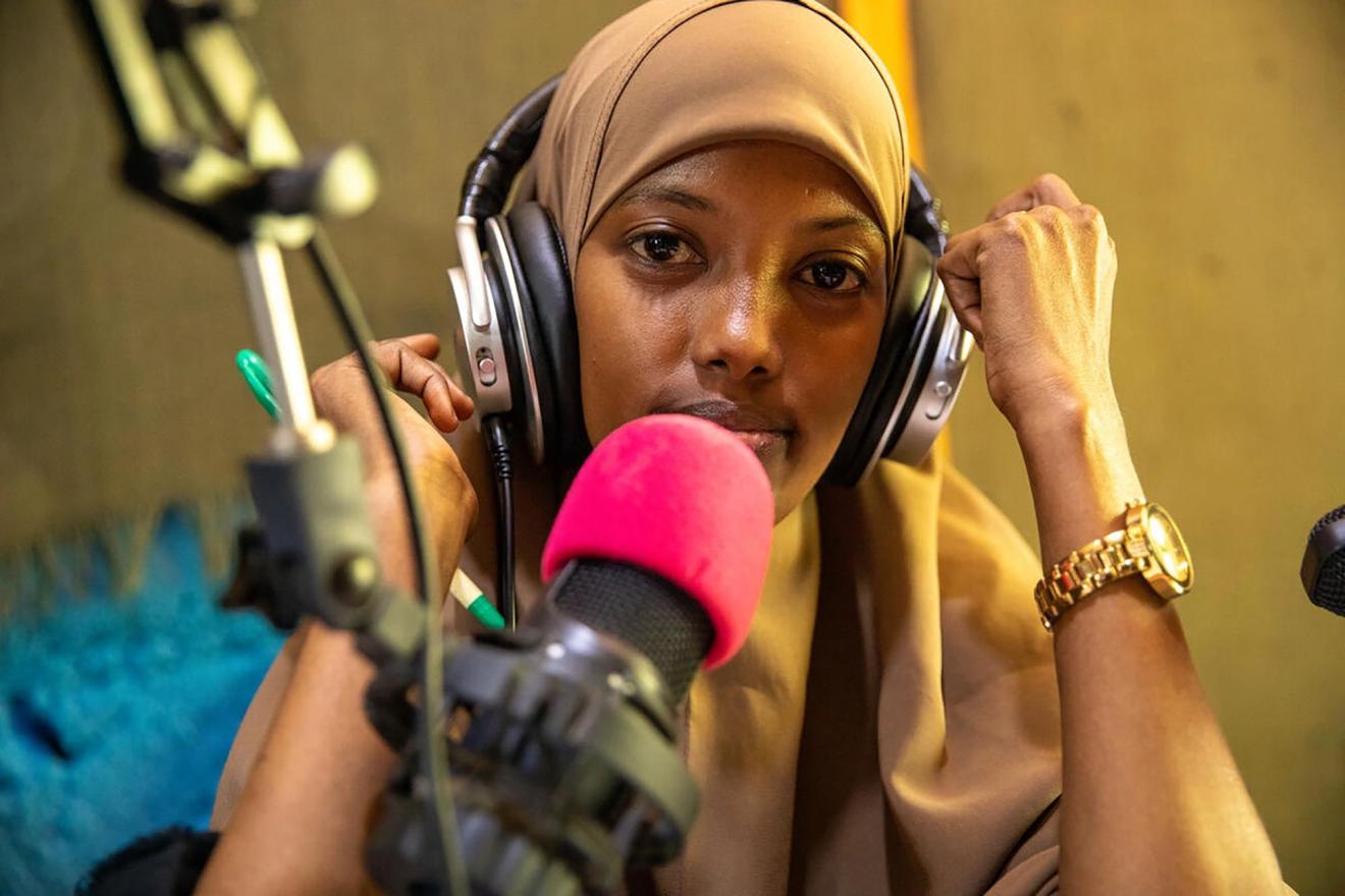 A medium shot of a woman wearing headphones in a radio station.