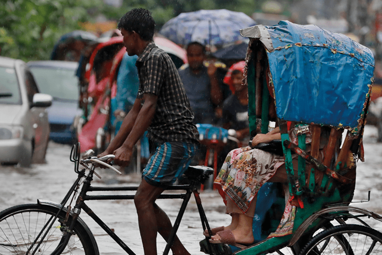 A young man ferrying a passenger on a bicycle taxi.