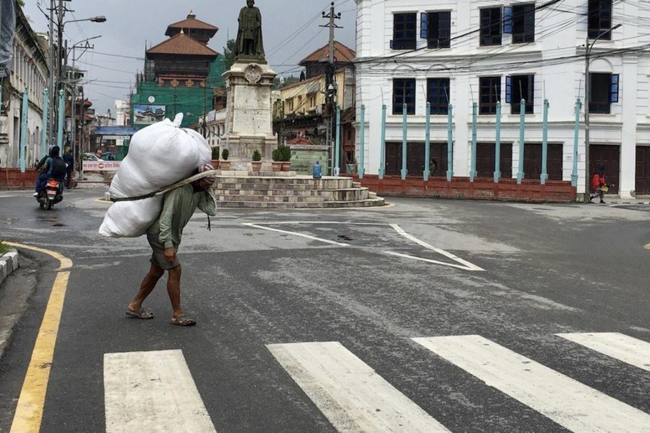 UN News\Vibhu Mishra. A daily-wage earner carrying goods on his back at a market in Nepal.