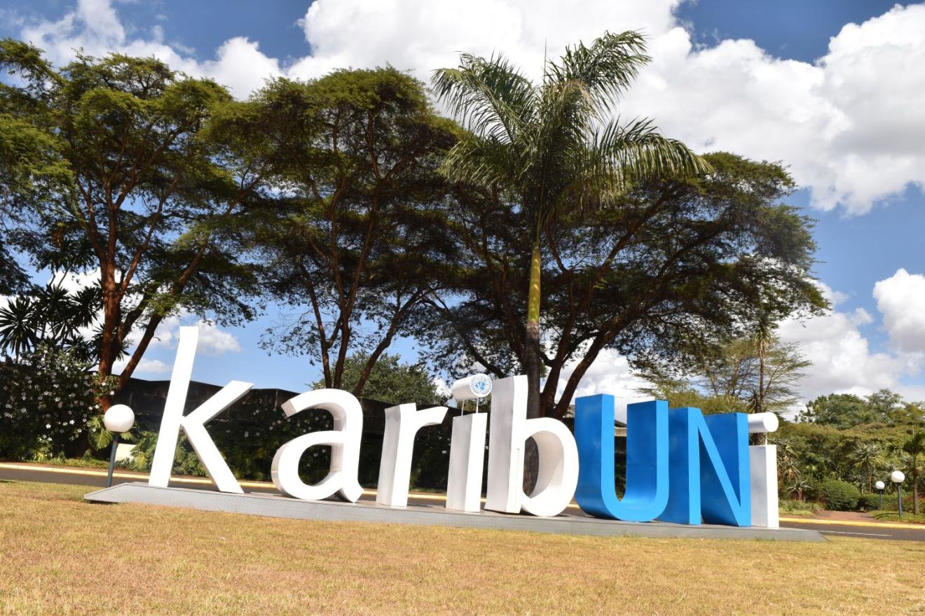 A wide-angle photograph of the United Nations Office at Nairobi showcases a prominent sign bearing the word “KARIBUNIT”.