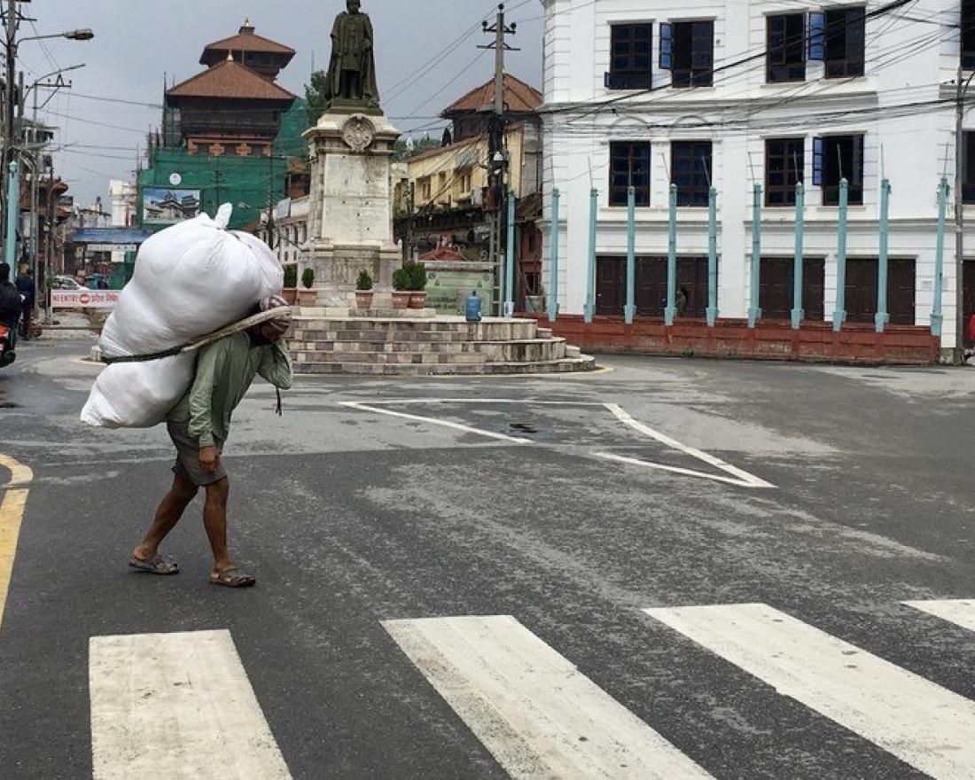 UN News\Vibhu Mishra. A daily-wage earner carrying goods on his back at a market in Nepal.