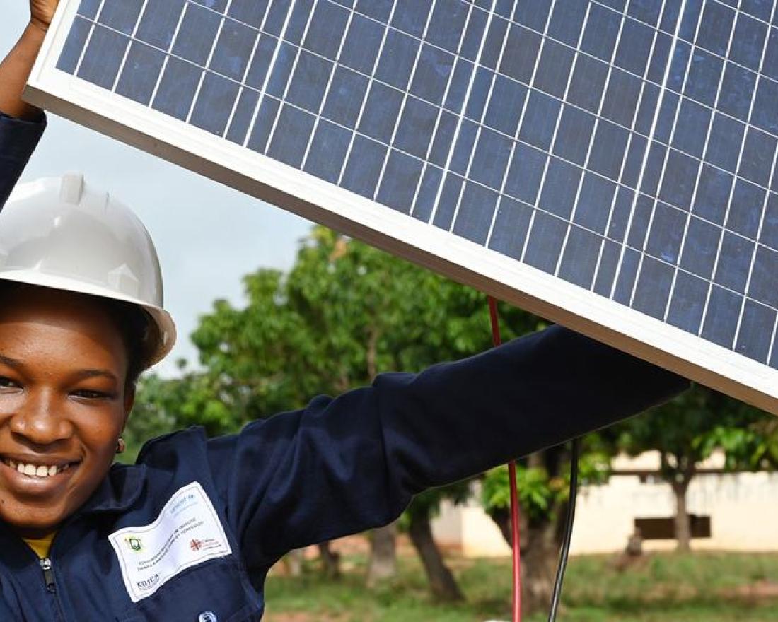 © UNICEF/Frank Dejongh. A teenage woman in Côte d'Ivoire holds up a solar panel which she is studying as part of a renewable energy course.