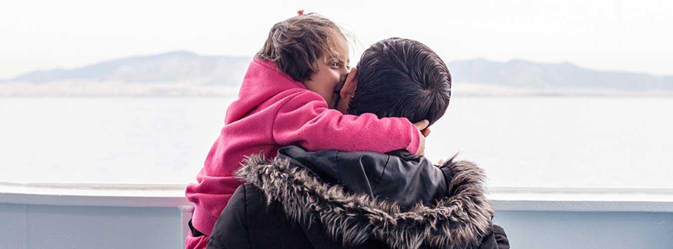 Une petite fille réfugiée dans les bras de son papa, à bord d'un bateau.