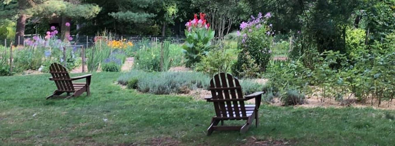 Des chaises de jardin devant un parterre de fleurs