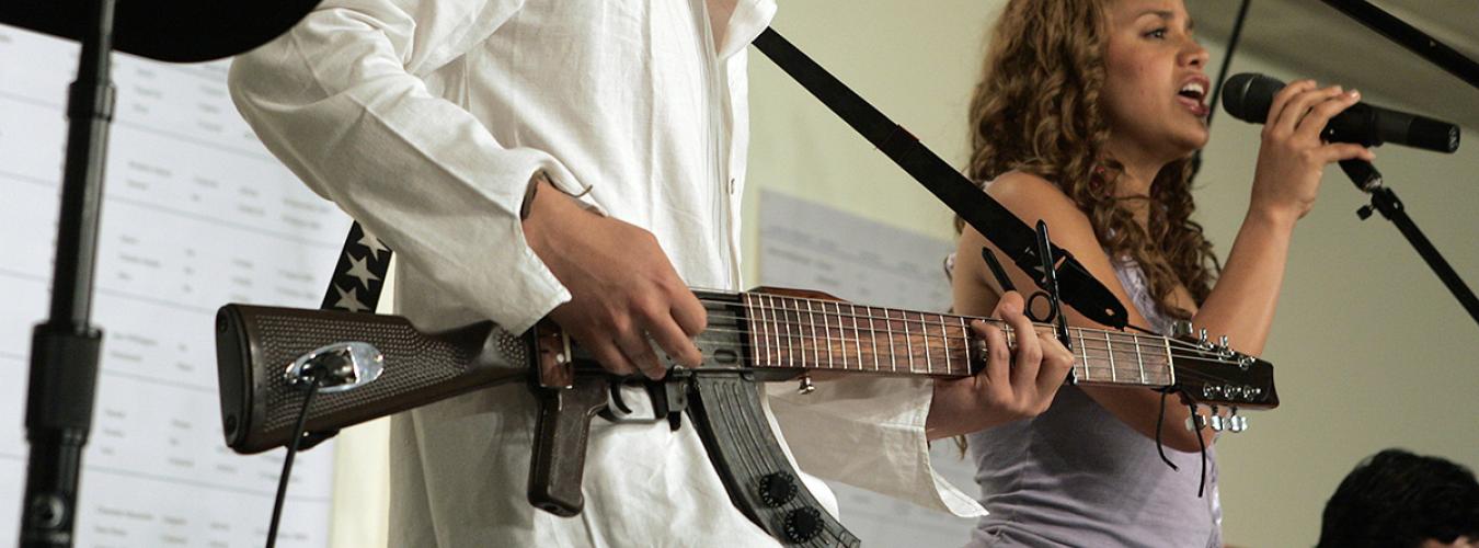 Musician playing an "escopetarra," a guitar made from an AK-47