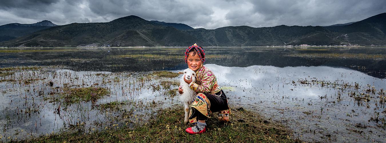 Un enfant avec son animal de compagnie et les montagnes en arrière-plan.