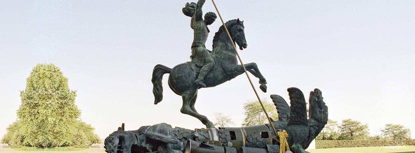 Escultura de un hombre a caballo, y un dragón que yace en el suelo.