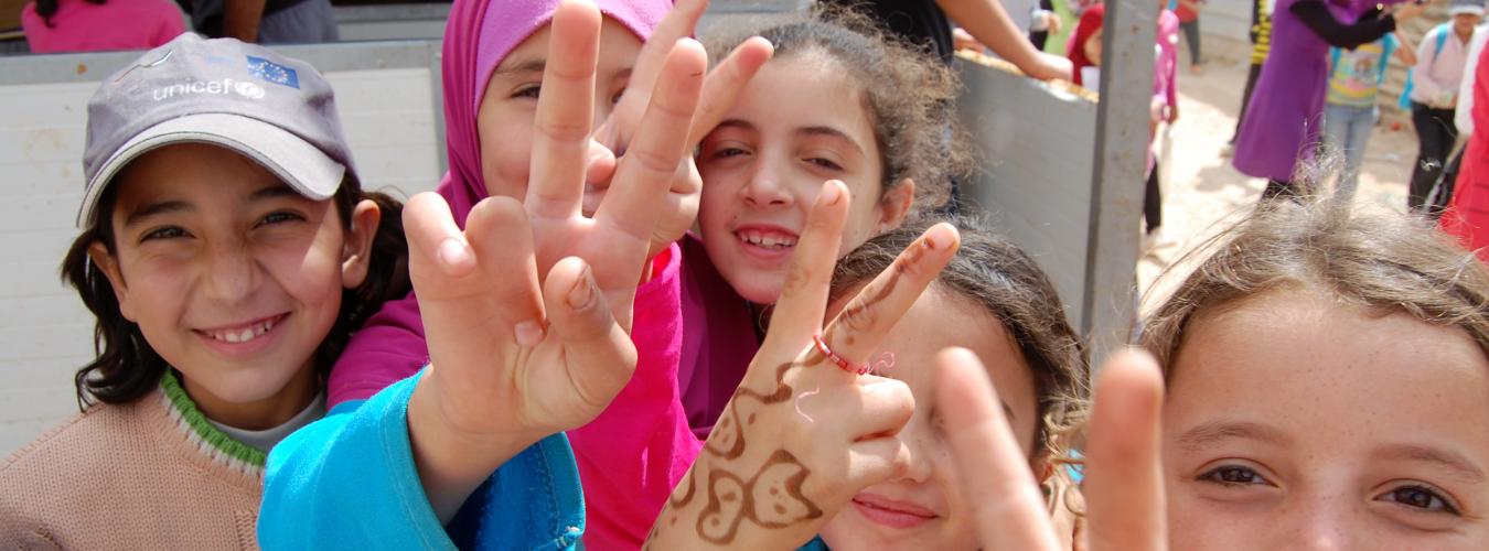 Des enfants réfugiés font le signe « V » de la paix avec leurs mains.