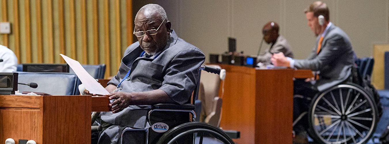Un homme en chaise roulante dans une salle de conférence de l’ONU, à New York.