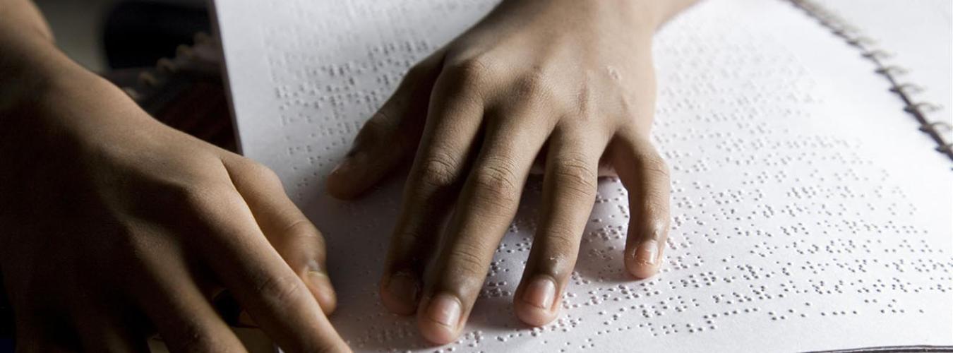 child reads paper printed in the Braille alphabet