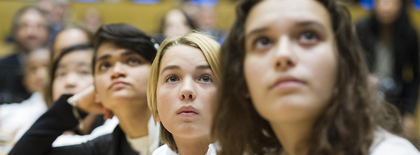 Rostros de unas chicas mirando hacia el frente de la sala.