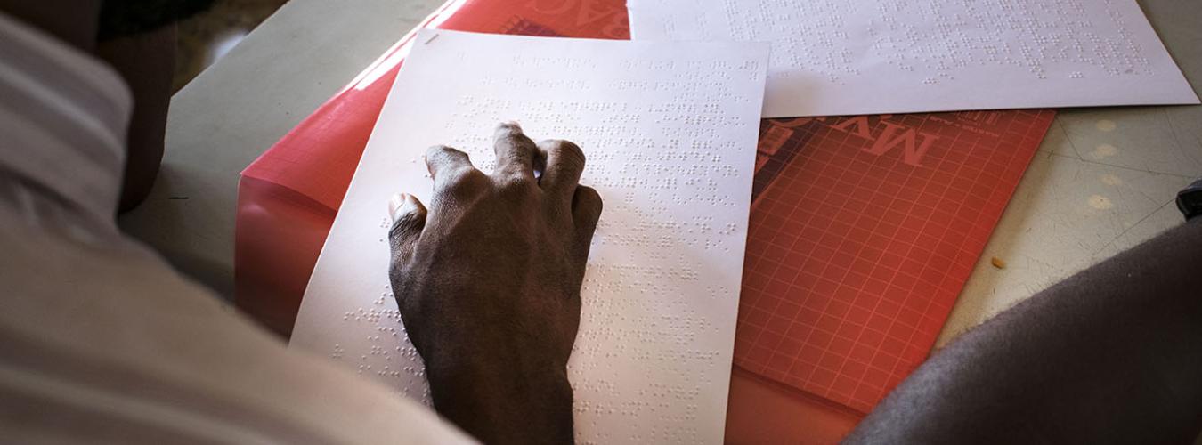 Antes de que se celebren elecciones en Sierra Leona, un oficial de capacitación lee una guía de votación táctil para garantizar que las personas con discapacidad sepan cómo votar (2018).