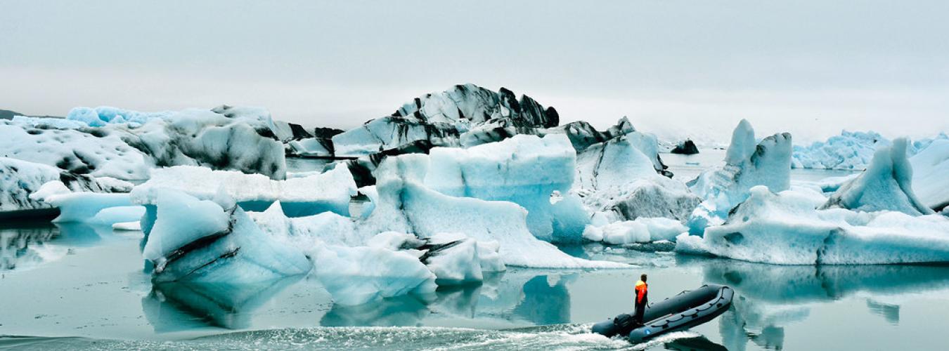 Boat in a lagoon with big blocks of ice crumble from a shrinking glacier
