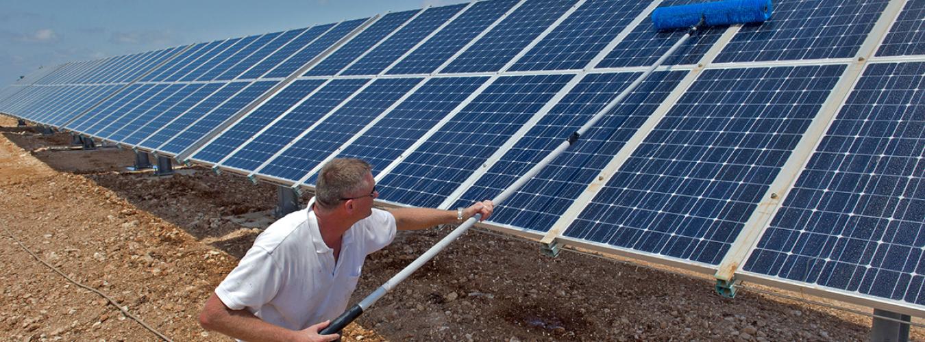 A man cleaning solar panels on a sunny day at UN facilities in Nqoura, Lebanon.