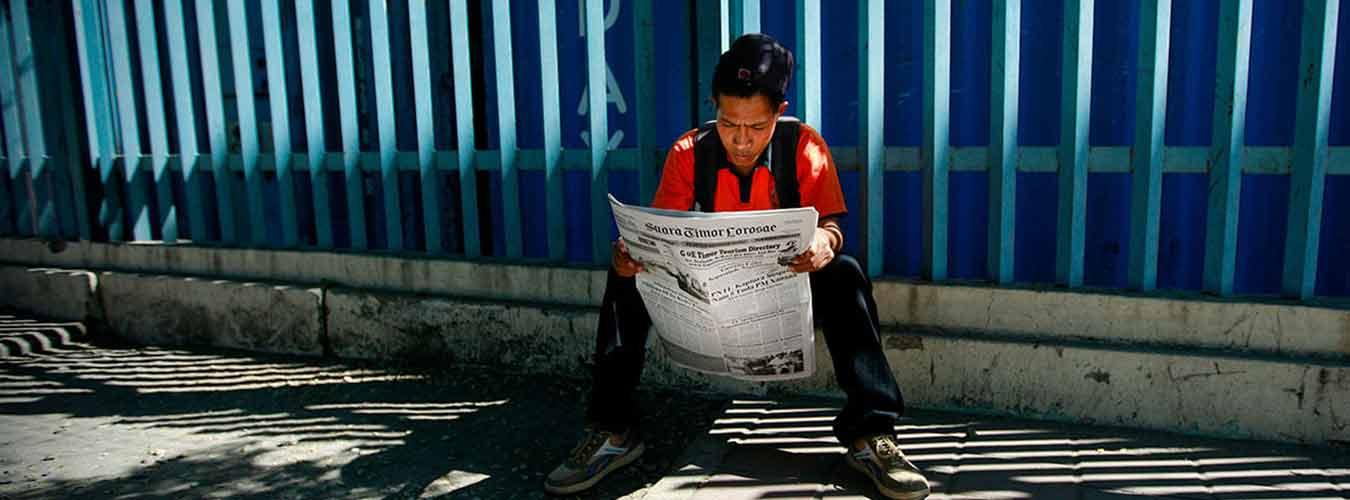 Un joven leyendo el periódico en una calle de Dili (Timor-Leste). 