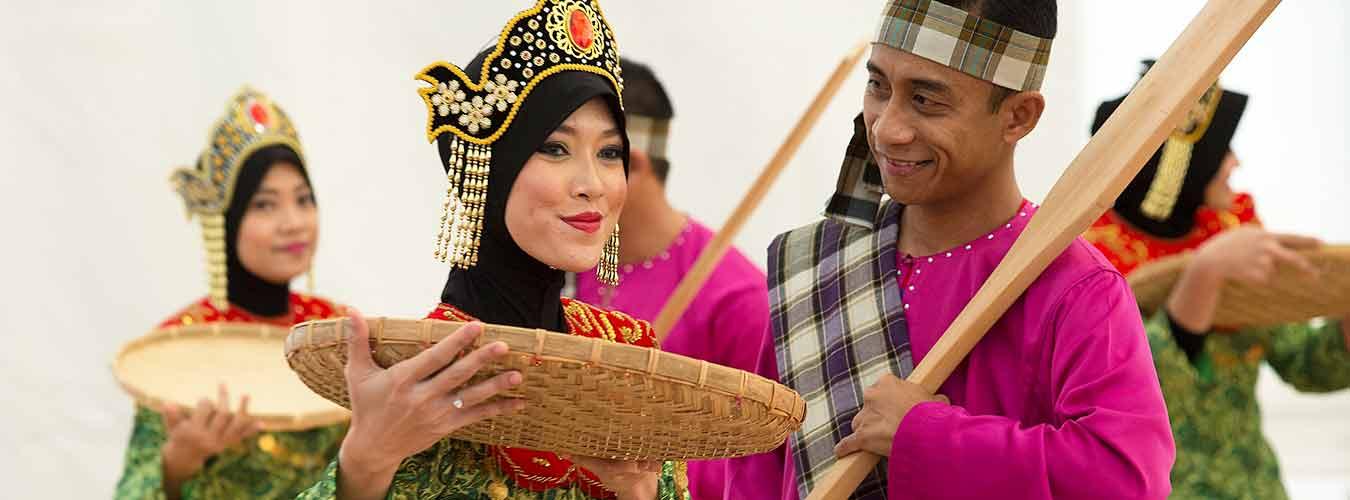 Women and men dressed in colorful traditional attire perform a dance.