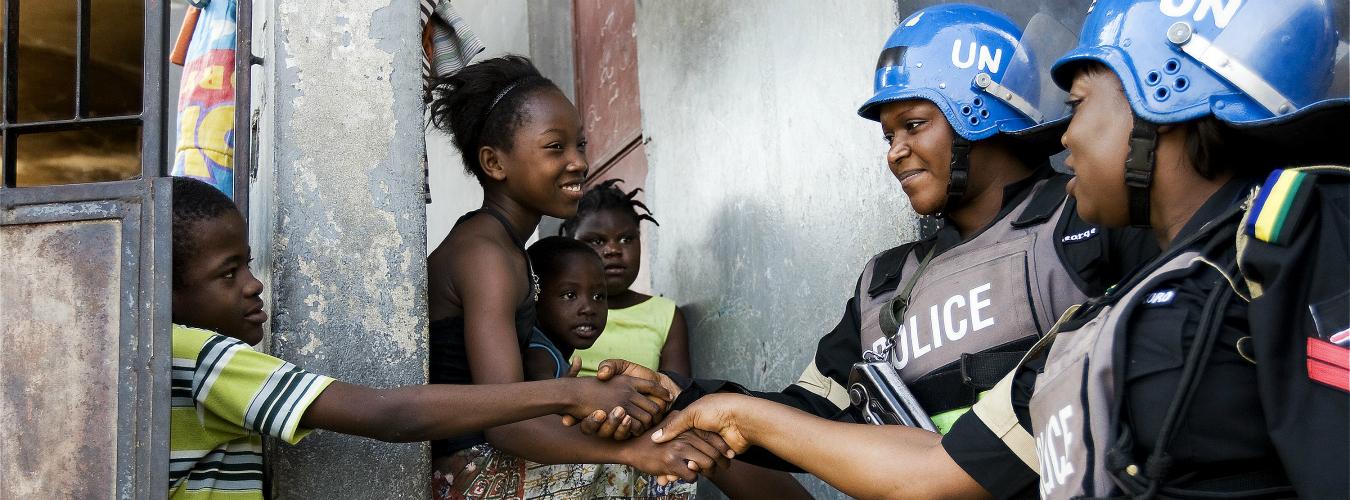 نيجيريتان من بعثة الأمم المتحدة في هايتي تتحدثان مع أطفال في أثناء دورتهن في حي فقير في العاصمة الهايتية بورت - أو -  برنس. انتهت ولاية بعثة الأمم المتحدة لتحقيق الاستقرار في هايتي في تشرين الأول/أكتوبر 2017. وأنقذت قوات حفظ السلام التابعة للبعثة خلال 13 