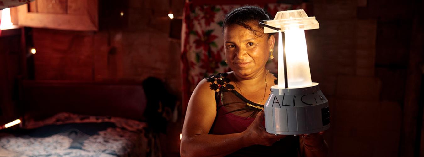 Mujer en el interior de una vivienda con una lámpara solar