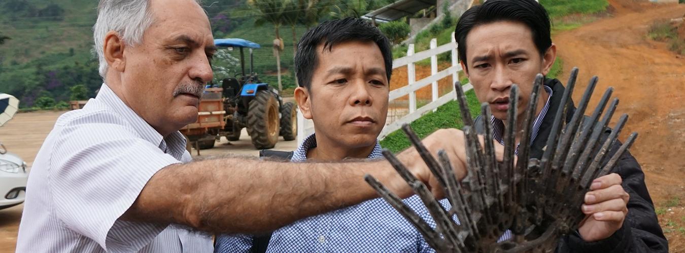 Three men checking a farming tool