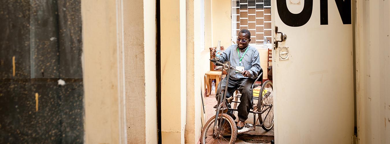 Un homme en chaise roulante dans le couloir d’une station de radio. 