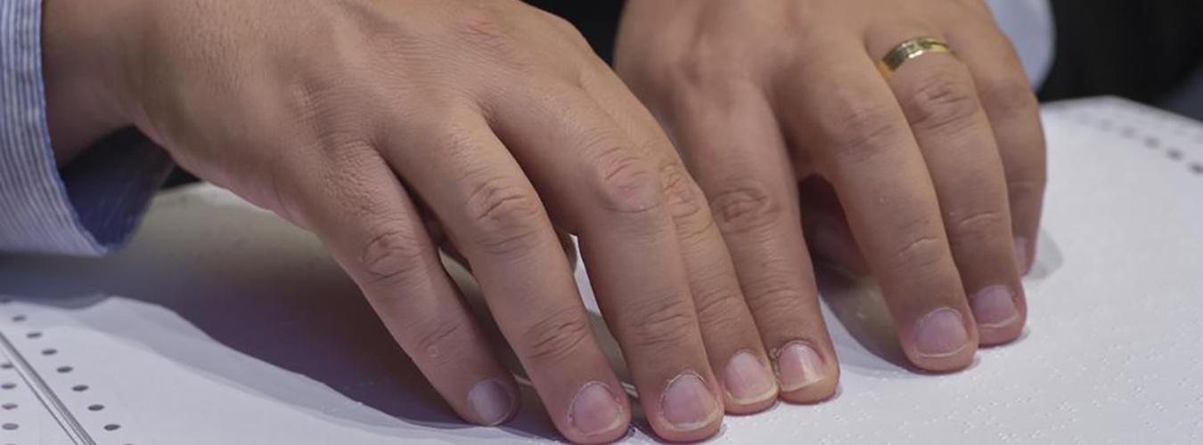 Close-up of hands reading braille.