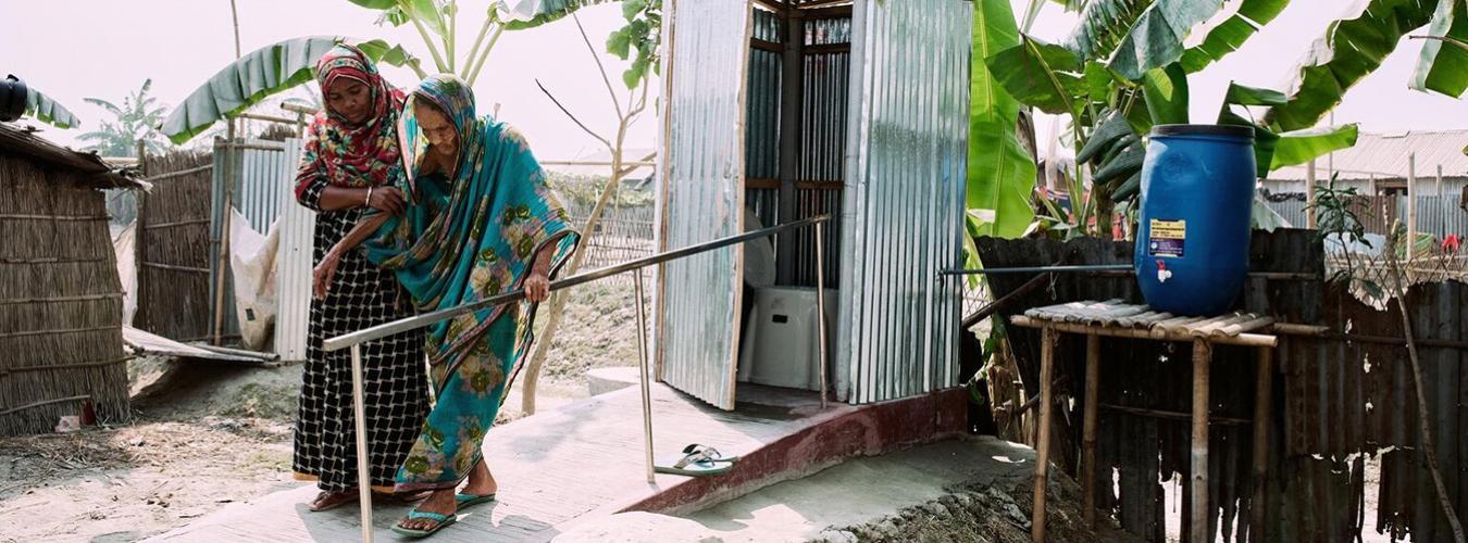 Une jeune femme aide une femme plus âgée qui sort des toilettes